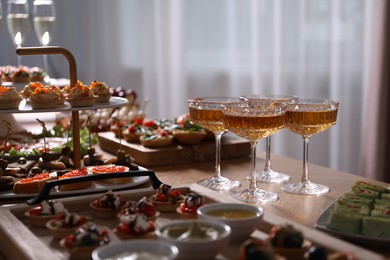 Photo of Buffet menu. Glasses of sparkling wine and tasty appetizers on table, closeup