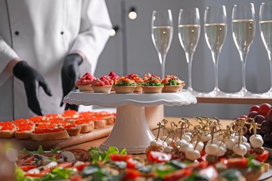 Photo of Chef arranging appetizers on buffet table, selective focus