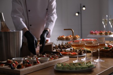Photo of Chef arranging appetizers on buffet table, selective focus