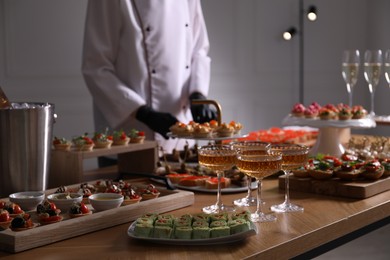 Photo of Chef arranging appetizers on buffet table, selective focus