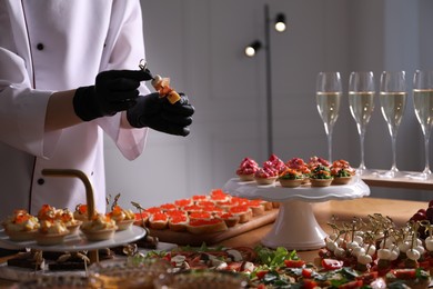 Photo of Chef arranging appetizers on buffet table, closeup