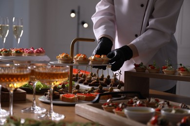 Photo of Chef arranging appetizers on buffet table, closeup
