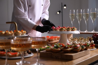 Photo of Chef arranging appetizers on buffet table, closeup
