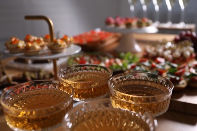 Photo of Buffet menu. Glasses of sparkling wine and tasty appetizers on table, closeup