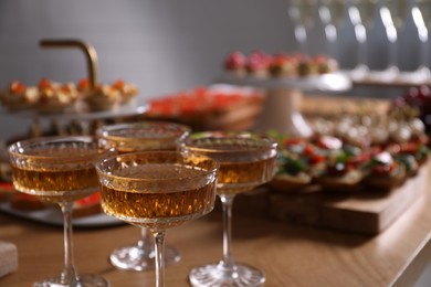 Photo of Buffet menu. Glasses of sparkling wine and tasty appetizers on table, closeup