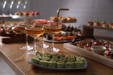 Photo of Buffet menu. Glasses of sparkling wine and tasty appetizers on table, closeup