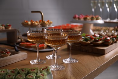Photo of Buffet menu. Glasses of sparkling wine and tasty appetizers on table, closeup