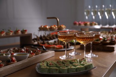 Photo of Buffet menu. Glasses of sparkling wine and tasty appetizers on table, closeup