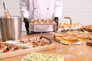 Photo of Chef arranging appetizers on buffet table, closeup