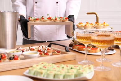 Photo of Chef arranging appetizers on buffet table, closeup