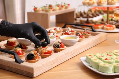 Photo of Chef arranging appetizers on buffet table, closeup