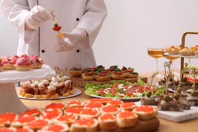 Photo of Chef arranging appetizers on buffet table, closeup