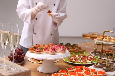 Photo of Chef arranging appetizers on buffet table, selective focus
