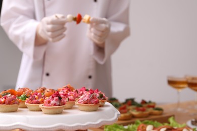 Photo of Chef arranging appetizers on buffet table, selective focus