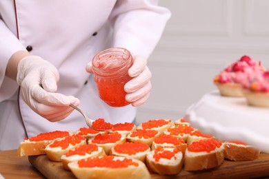 Photo of Chef making sandwiches with red caviar for buffet, closeup