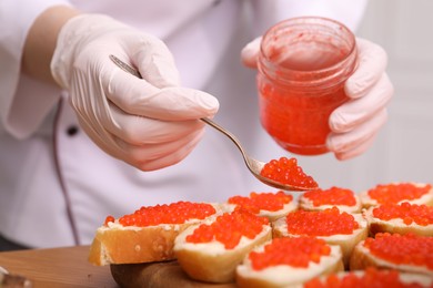 Photo of Chef making sandwiches with red caviar for buffet, closeup
