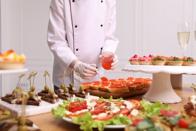 Photo of Chef making sandwiches with red caviar for buffet, closeup