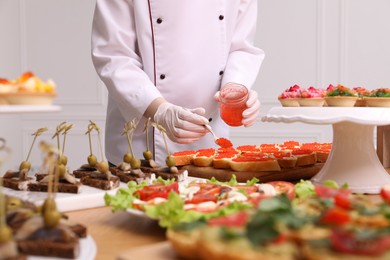 Photo of Chef making sandwiches with red caviar for buffet, closeup