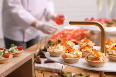Photo of Chef arranging appetizers on buffet table, selective focus