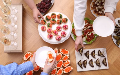 Photo of Buffet menu. People taking tasty appetizers from wooden table, top view