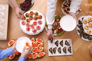 Photo of Buffet menu. People taking tasty appetizers from wooden table, top view