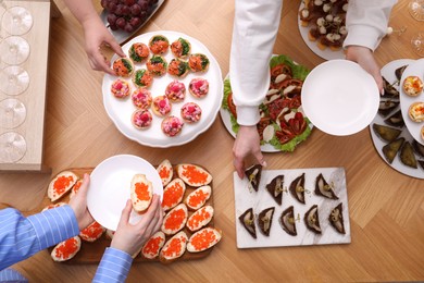 Photo of Buffet menu. People taking tasty appetizers from wooden table, top view