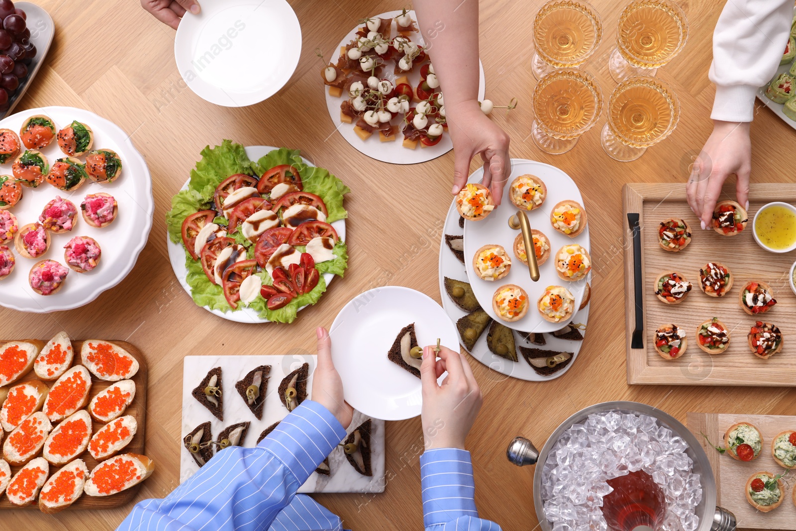 Buffet menu. People taking tasty appetizers from wooden table, top view Photo of Buffet menu. People taking tasty appetizers from wooden table, top view