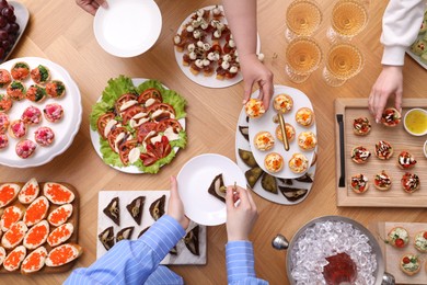 Photo of Buffet menu. People taking tasty appetizers from wooden table, top view