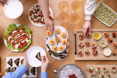 Photo of Buffet menu. People taking tasty appetizers from wooden table, top view