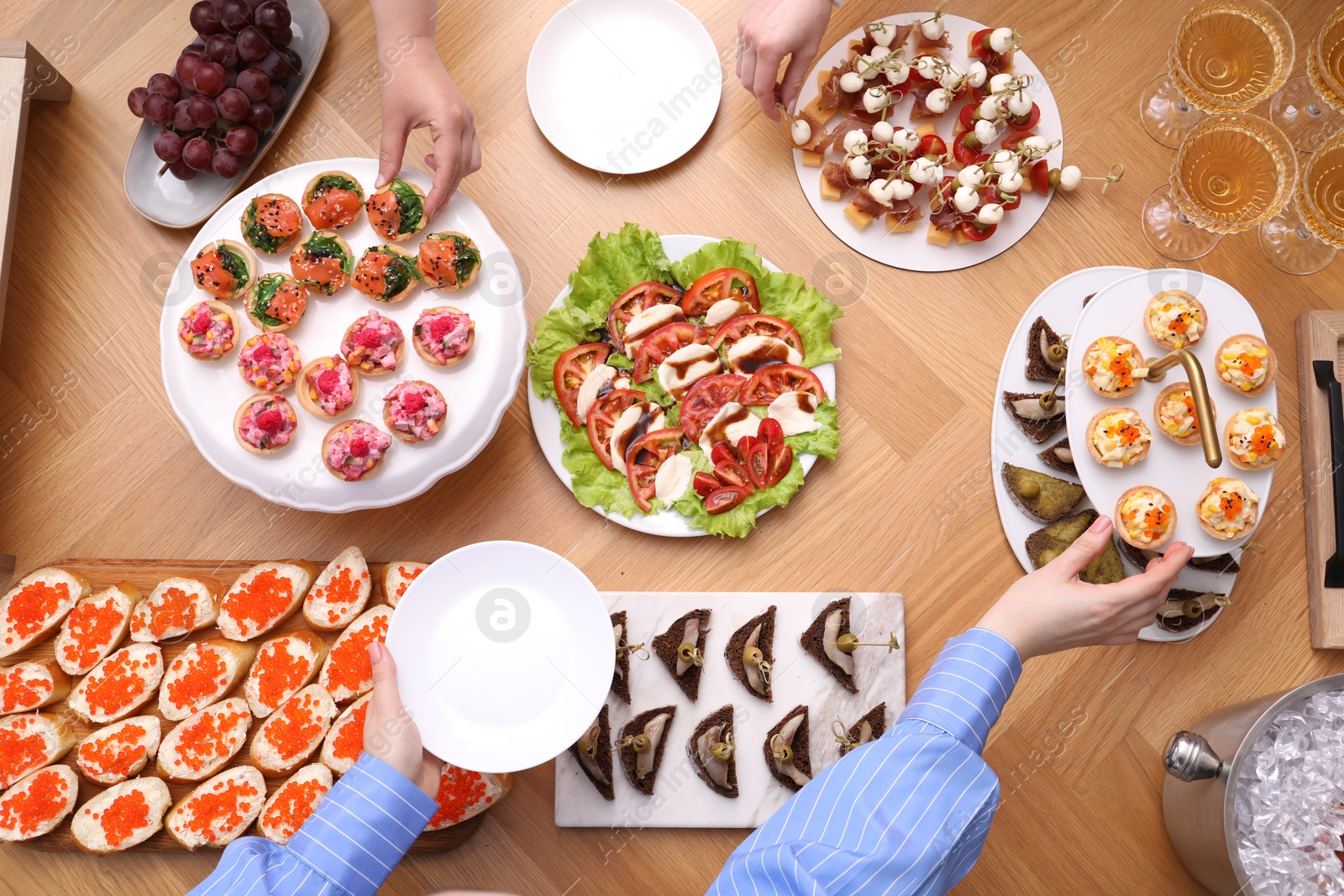 Buffet menu. People taking tasty appetizers from wooden table, top view Photo of Buffet menu. People taking tasty appetizers from wooden table, top view
