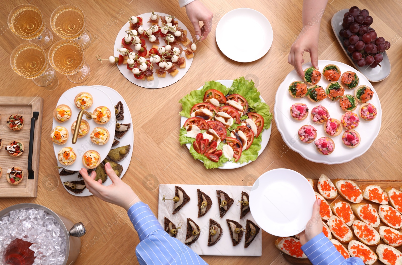 Buffet menu. People taking tasty appetizers from wooden table, top view Photo of Buffet menu. People taking tasty appetizers from wooden table, top view
