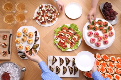 Photo of Buffet menu. People taking tasty appetizers from wooden table, top view