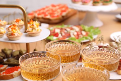 Photo of Buffet menu. Glasses of sparkling wine and tasty appetizers on table, closeup