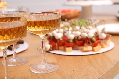 Photo of Buffet menu. Glasses of sparkling wine and tasty appetizers on table, closeup