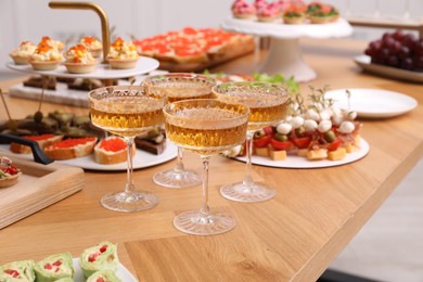 Photo of Buffet menu. Glasses of sparkling wine and tasty appetizers on table, closeup