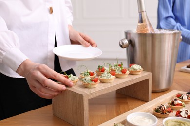 Photo of Buffet menu. Woman taking tasty tartlet from table, closeup