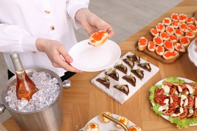 Photo of Buffet menu. Woman with tasty sandwich at table, closeup