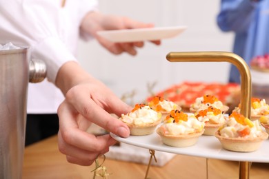 Photo of Buffet menu. Woman taking tasty tartlet from table, closeup