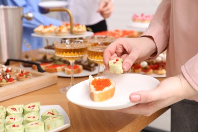 Photo of Buffet menu. Woman taking tasty appetizers from table, closeup