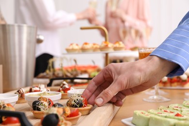 Photo of Buffet menu. Woman taking tasty tartlet from table, closeup