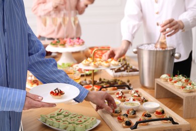 Photo of People with different appetizers at buffet, closeup