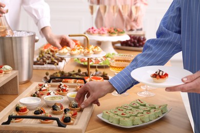 Photo of People with different appetizers at buffet, closeup