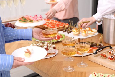 Photo of People with different appetizers at buffet, closeup
