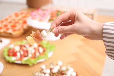 Photo of Buffet menu. Woman taking tasty canape from table, closeup