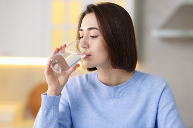 Photo of Young woman drinking water from at home