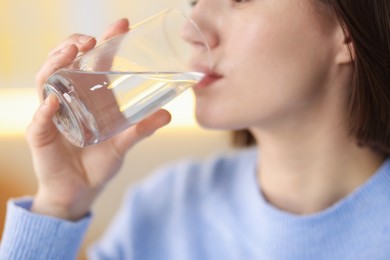 Photo of Young woman drinking water from at home, closeup