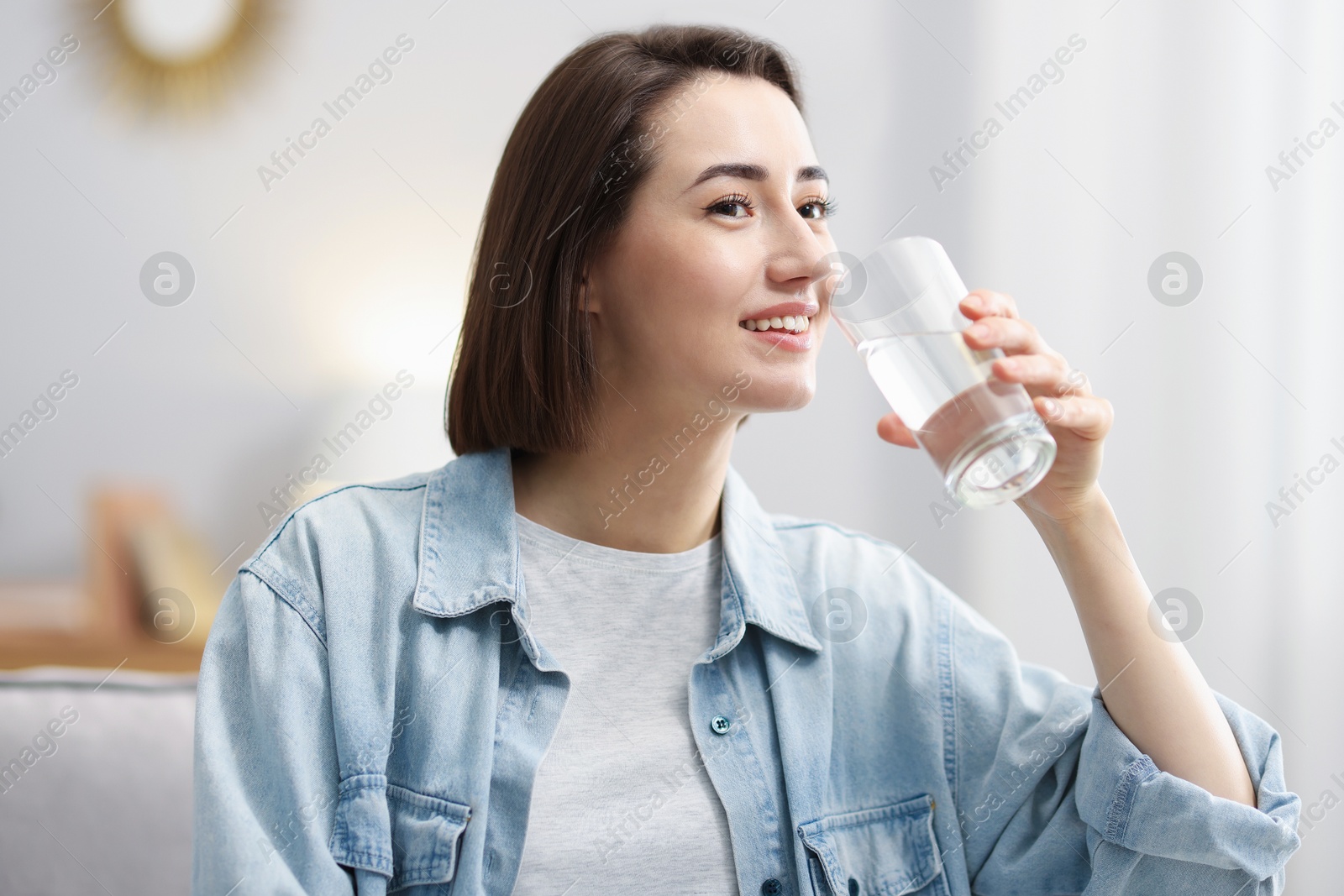 Young woman drinking water from at home Photo of Young woman drinking water from at home