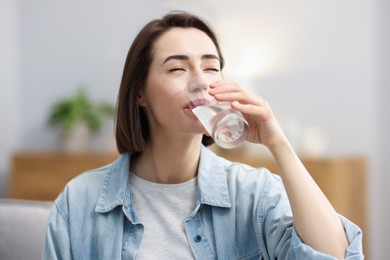 Photo of Young woman drinking water from at home