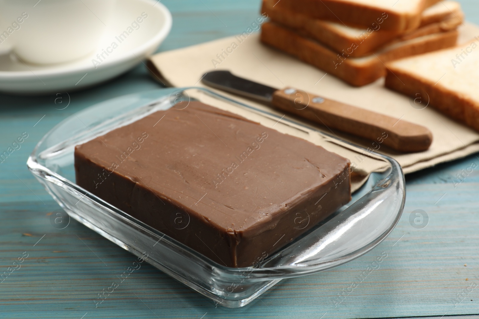 Block of tasty chocolate butter in glass keeper on light blue wooden table, closeup Photo of Block of tasty chocolate butter in glass keeper on light blue wooden table, closeup