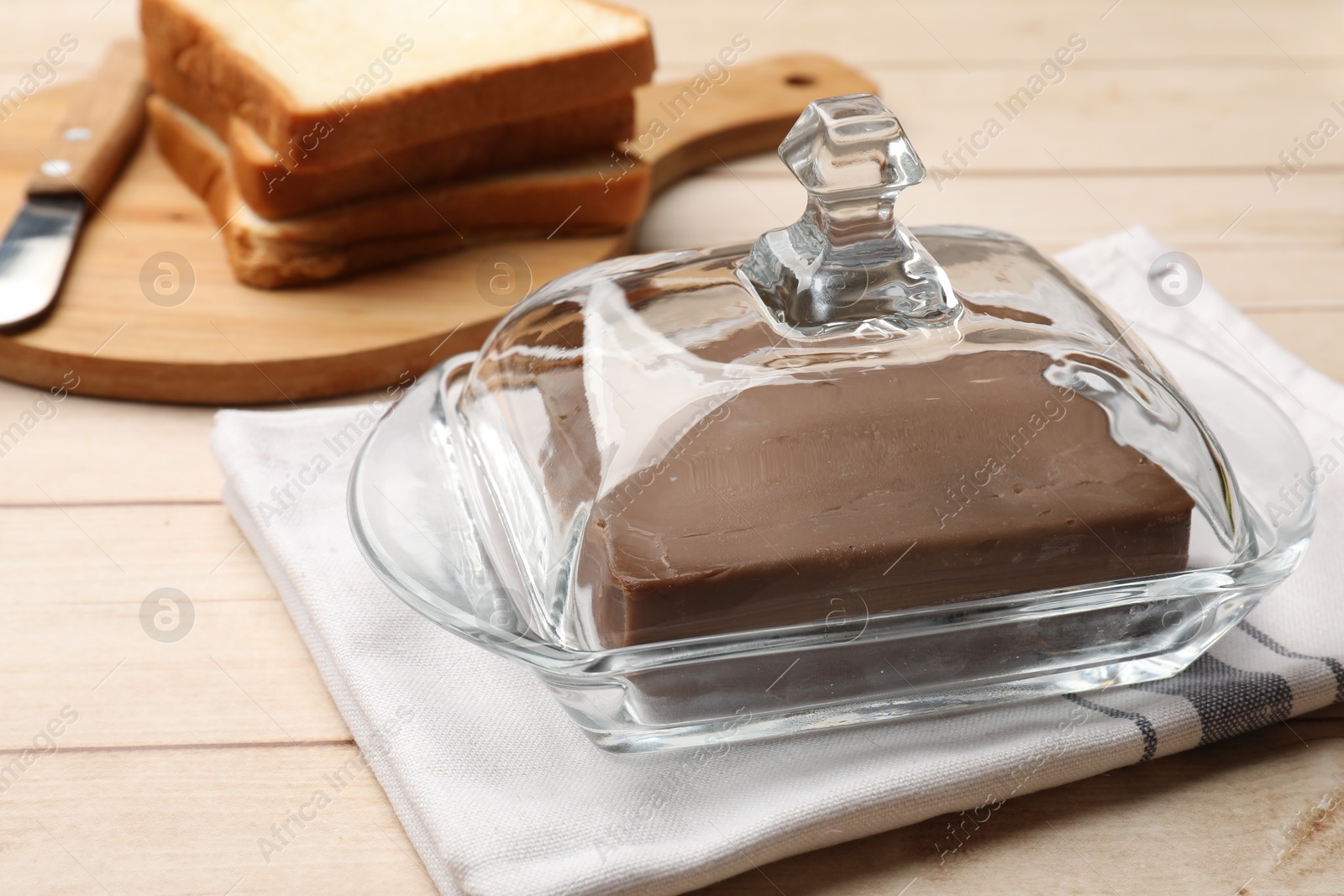 Block of tasty chocolate butter in glass keeper on light wooden table, closeup Photo of Block of tasty chocolate butter in glass keeper on light wooden table, closeup